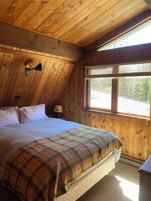 A wooden cabin bedroom with a bed, a window, and a ceiling fan. - Water's Edge Cottage - New 2026! (Castine)