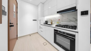 A modern kitchen with white cabinetry, a gas stove, an oven, and a built-in microwave. - Free Housekeeping Visits During Your Stay - Stayshort - Studio in Jumeirah Village Circle for 2 With Balcony (Dubai)