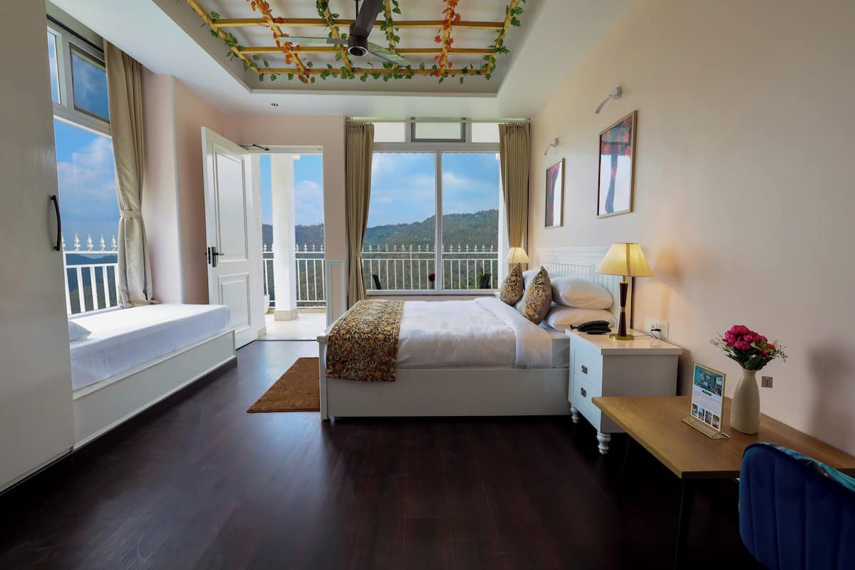 A bedroom with a bed, bedside table, lamp, and a view of a balcony.