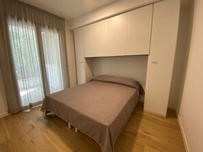 Ein Schlafzimmer mit einem Bett, einem Kleiderschrank und einem Fenster mit Vorhängen.