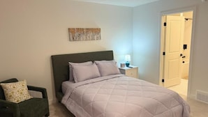 A bedroom with a bed, a chair, a nightstand, a lamp, and a door. - Modern Retreat 3BR 2&half Bath (Edmonton)
