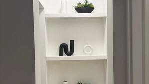 A white interior with a built-in shelf unit, a potted plant, and a white vase. - Modern Retreat 3BR 2&half Bath (Edmonton)