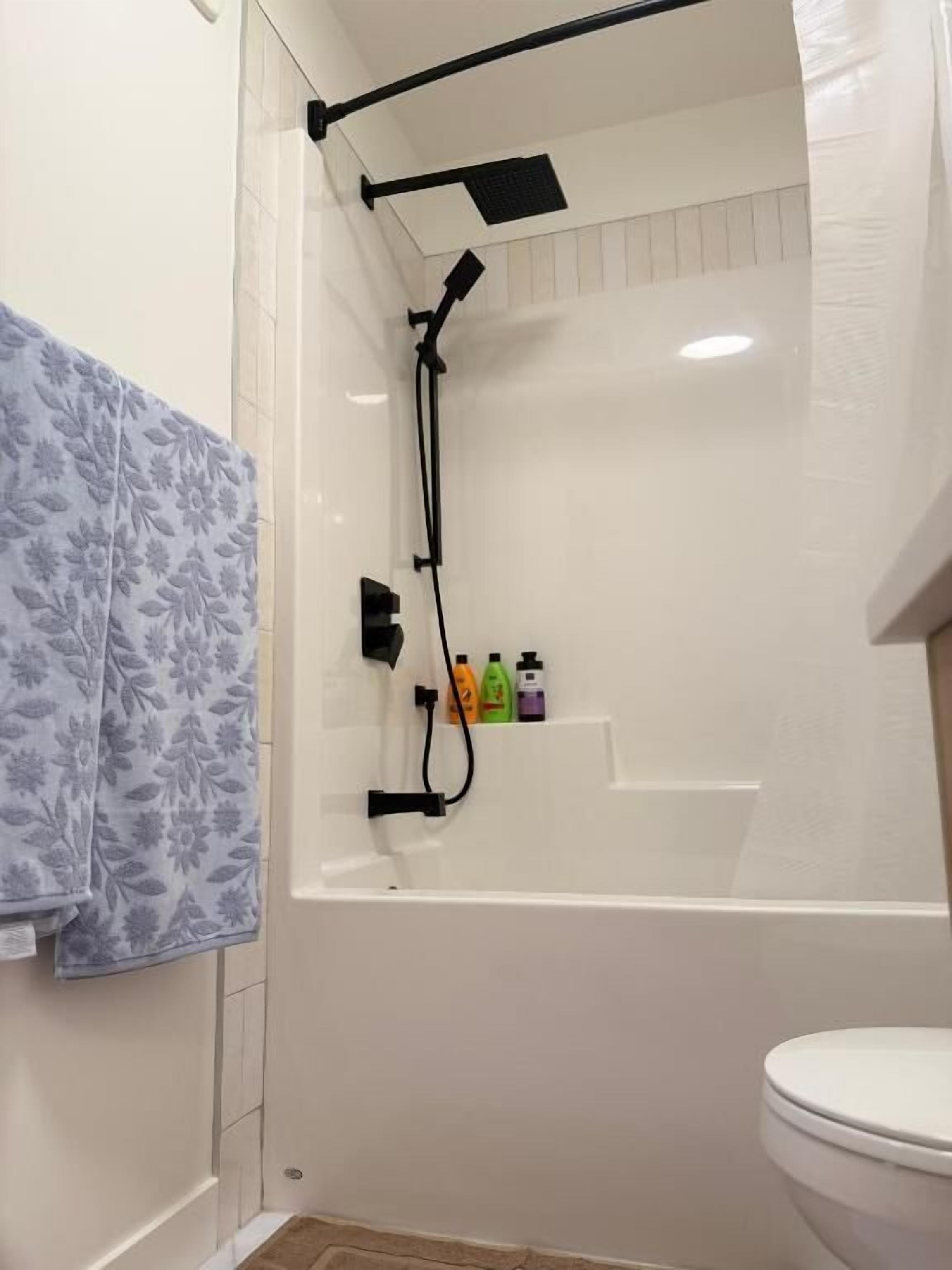 Un bagno con doccia, servizi igienici e un portasciugamani con un asciugamano decorato.