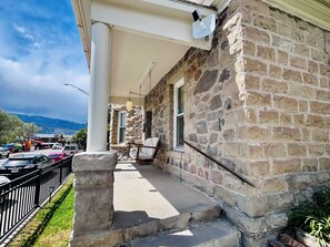 A stone building with a porch, a swing, and a view of the mountains.