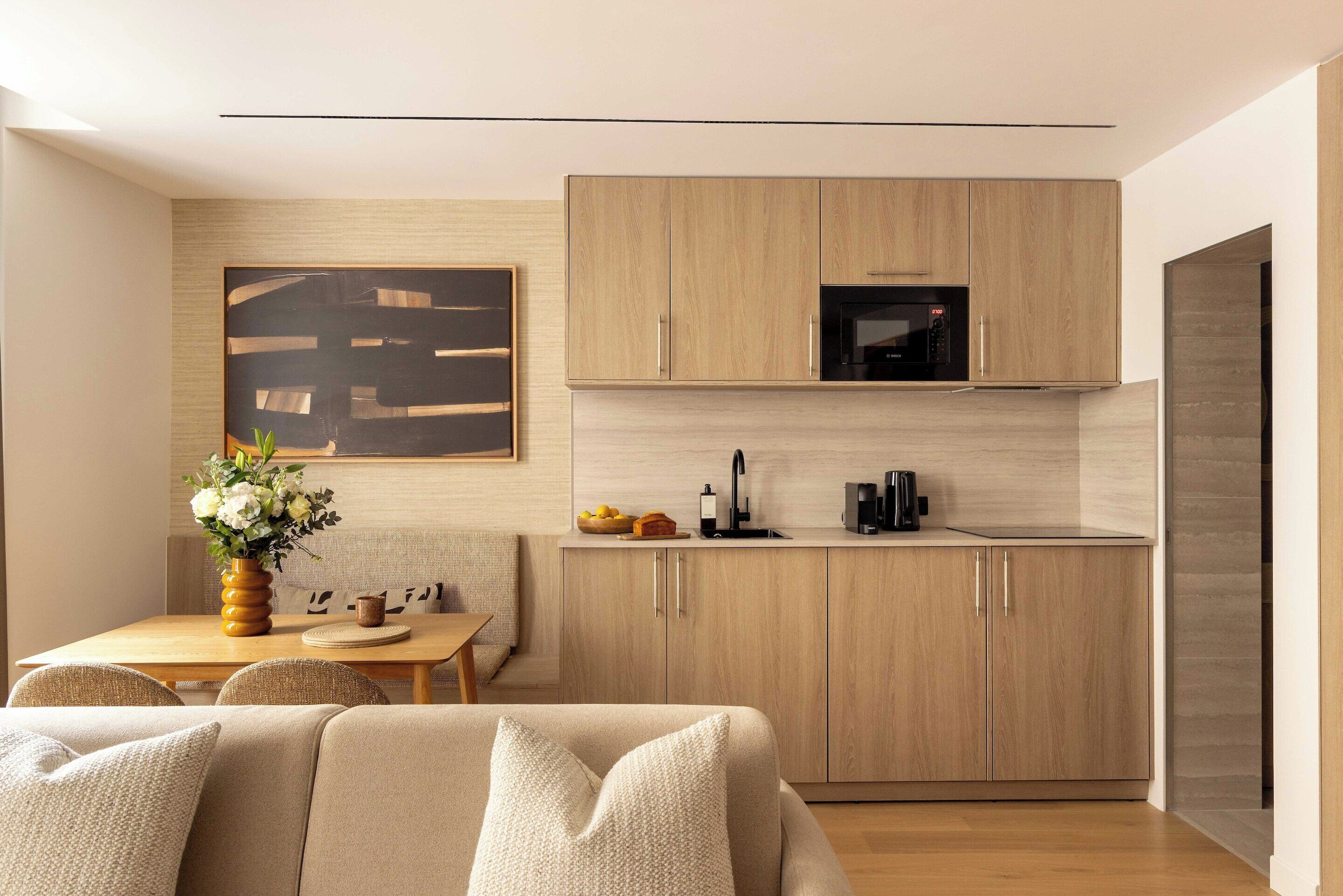 A modern kitchen with wooden cabinets, a microwave, and a dining area with a table and chairs.