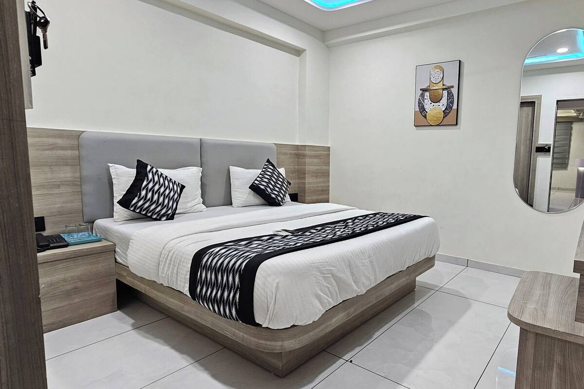 Un dormitorio moderno con una cama, mesitas de noche, un espejo y una obra de arte en la pared.