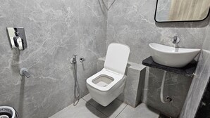 A bathroom with a toilet, bidet, and sink. - Hotel HR Sky (Ahmedabad)