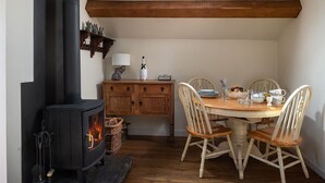 Una habitación acogedora con una estufa de leña, una mesa de comedor con sillas y una ventana sobre la estufa.
