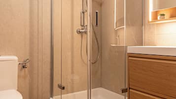A bathroom with a glass-enclosed shower, a toilet, and wooden cabinetry.