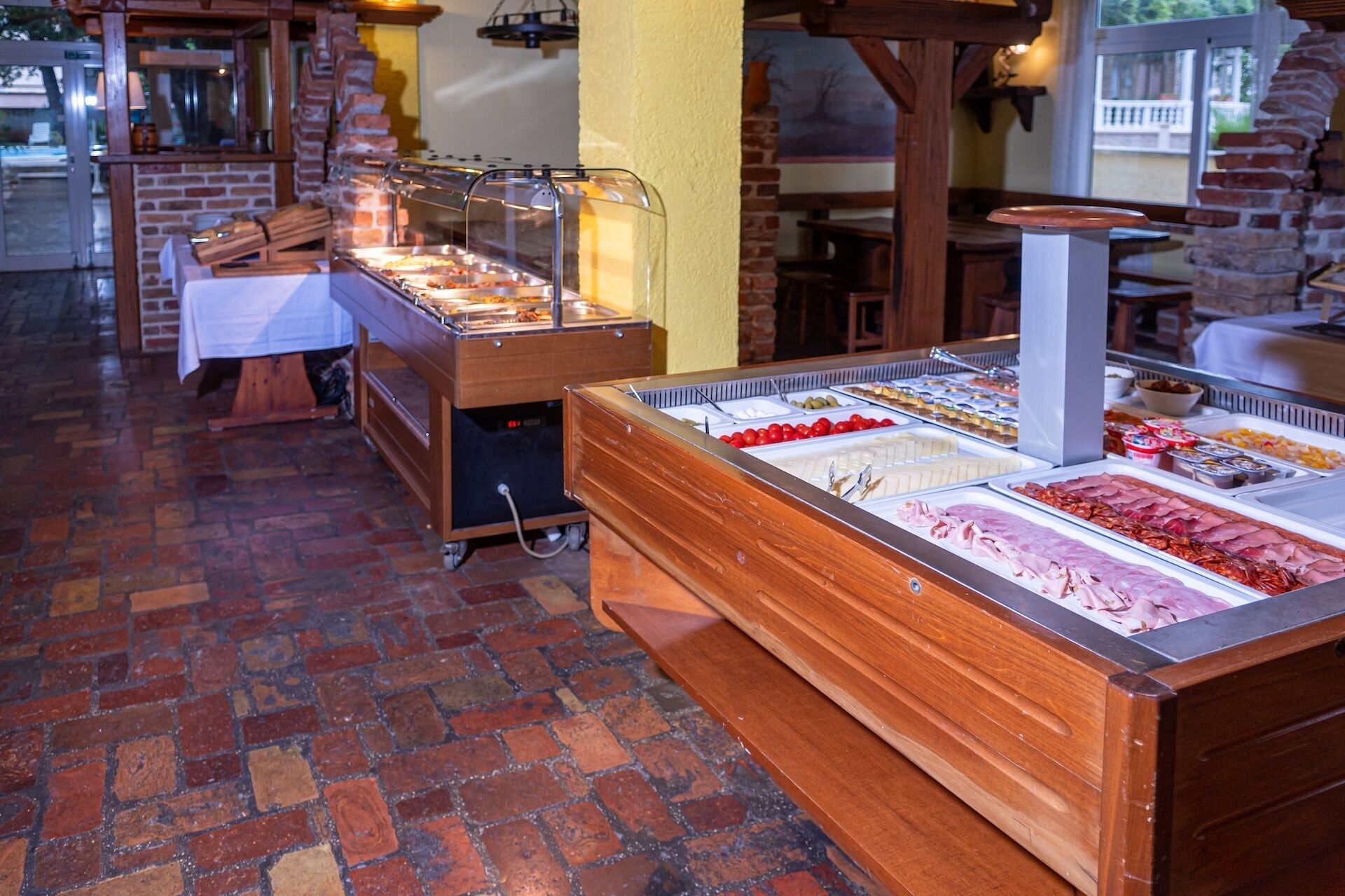 A buffet with various food items, a brick floor, and a brick wall.