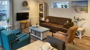 A living room with a brown sofa, teal armchairs, a coffee table, and a TV. - De Ankergooi! (Hardenberg)