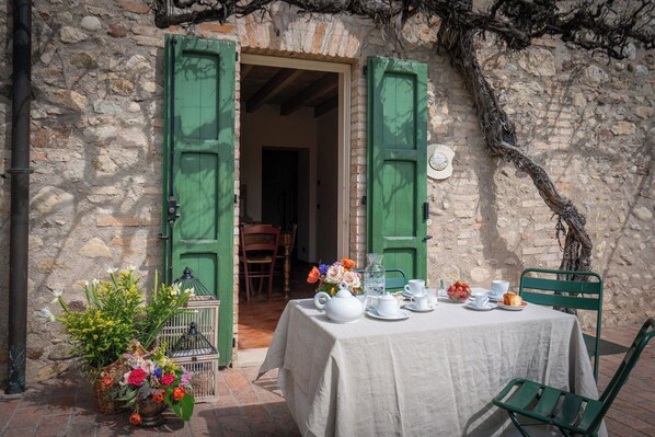 A table set for tea with a view of a stone building and green shutters.