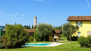 Un cortile con piscina, una torre e un edificio giallo.