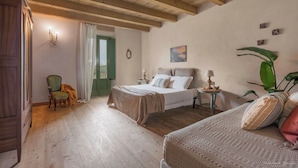 Une chambre avec deux lits, un plancher en bois, une porte verte et une grande plante.