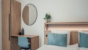 A bedroom with a bed, a desk, a chair, a wardrobe, a mirror, and a potted plant. - Apartment in Breskens Near the Beach (Breskens)