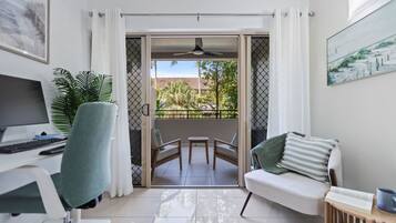 Quarto com escrivaninha, cadeira, sofá e varanda com mesa e cadeiras.