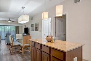A modern kitchen with a granite countertop, wooden cabinets, and a central island. - 2BR With Jacuzzi Arcade 10 Mins to Parks (Orlando)