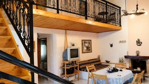 A loft-style room with a wooden staircase, a television, a sofa, a dining table, and a fireplace. - Vicky s Sweet Home - Seaside Retreat in Evia (Mantoudi-Limni-Agia Anna)