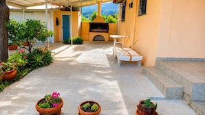 A covered outdoor area with a barbecue grill, seating, and potted plants. - Vicky s Sweet Home - Seaside Retreat in Evia (Mantoudi-Limni-Agia Anna)