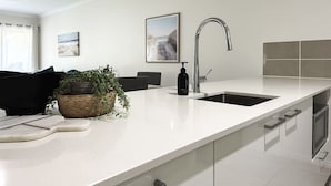 A modern kitchen with a white countertop, stainless steel sink, and a ceiling fan. - The Nook - Pet Family-friendly 4-bedroom (Cairns)