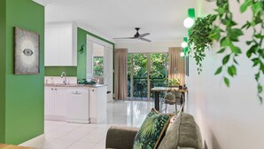 A modern living room with a sofa, a dining table, and a kitchen in the background. - Tropical Resort Escape (Cairns)