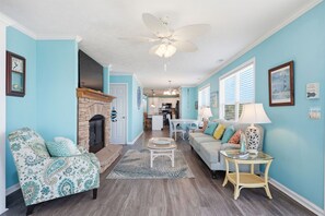 A living room with a fireplace, a sofa, a coffee table, and a dining area in the background. - Shackleford View Beach (Pet Friendly/Private Beach) (Harkers Island)