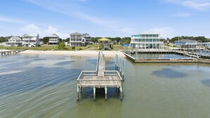 Een pand aan het water met een houten steiger die uitloopt op een pier, omringd door woongebouwen.
