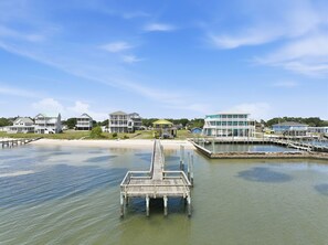 A waterfront property with a wooden dock leading to a pier, surrounded by residential buildings. - Shackleford View Beach (Pet Friendly/Private Beach) (Harkers Island)