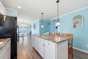 A kitchen with a black refrigerator, granite countertop, white cabinets, and pendant lights. - Shackleford View Beach (Pet Friendly/Private Beach) (Harkers Island)