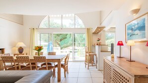 A spacious room with a dining table, chairs, a sofa, a TV, and a kitchen area. - Luxury Golf & Ocean Villa Escape (Lacanau)