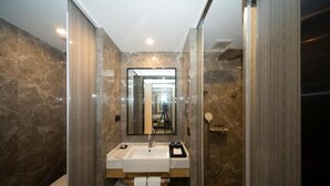 Un baño moderno con lavamanos de mármol, un espejo, ducha e inodoro.