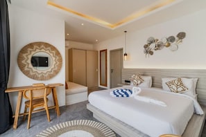 A modern hotel room with a large bed, a desk, a chair, a round mirror, and a wall art piece. - Majys 1 Villa by Tasvan (Badung)
