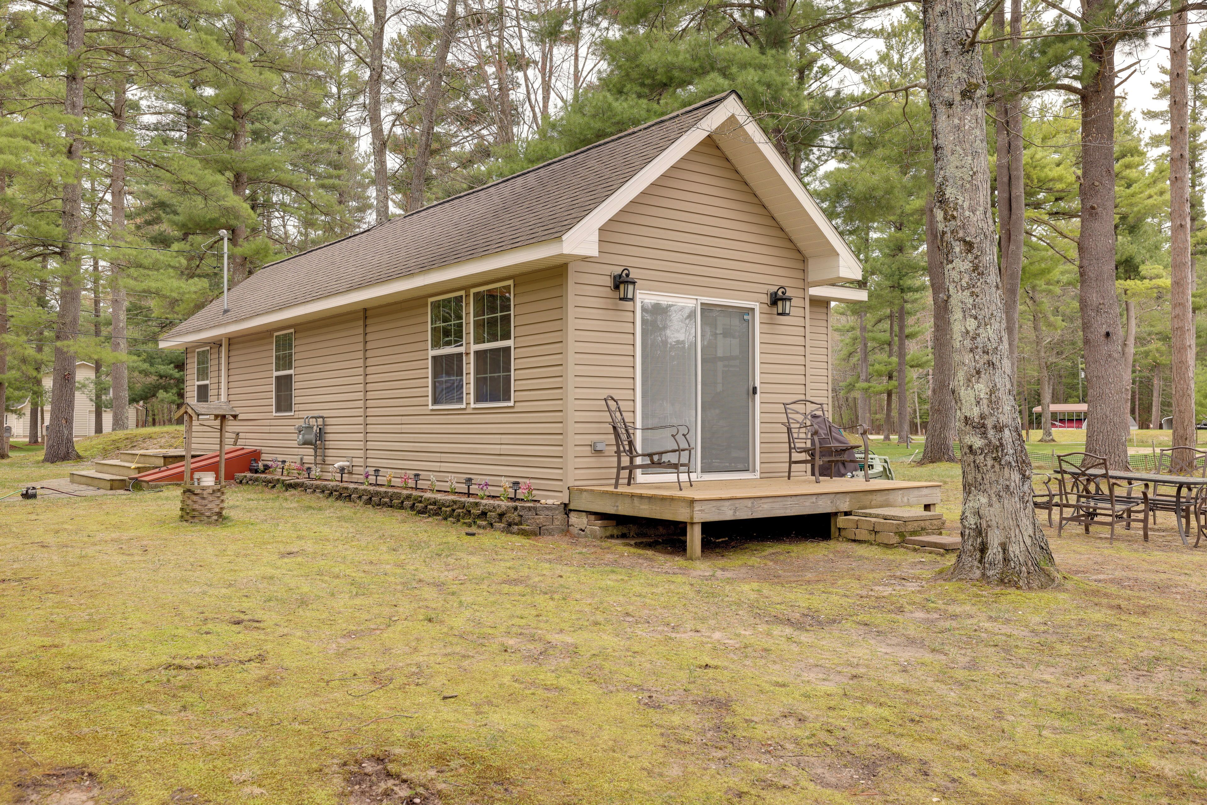A small cabin with a deck, surrounded by trees.