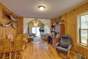A wooden interior with a dining area, a living room, and a desk with a computer. - Torch River Cabin Retreat: Relax on the Water! (Rapid City)