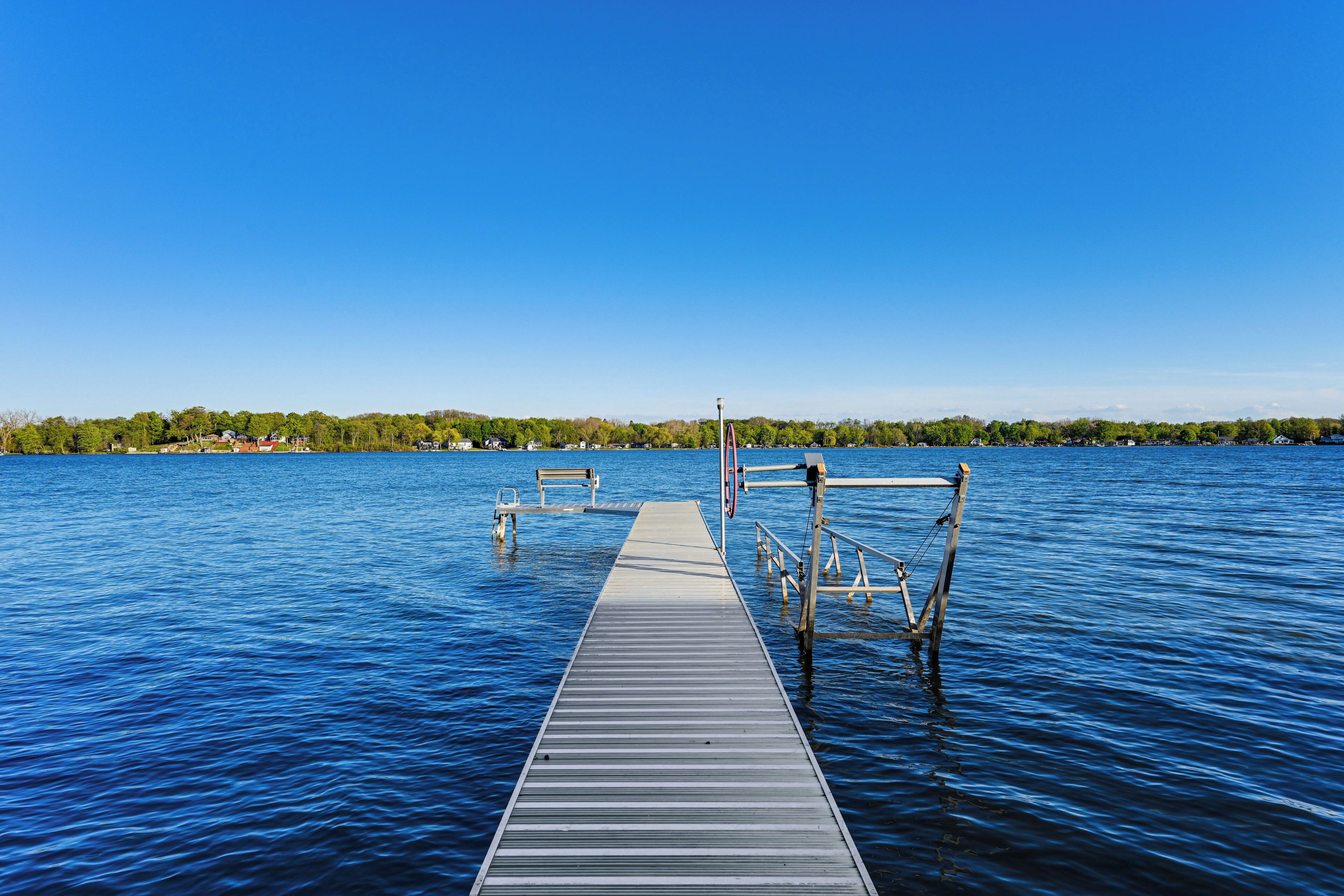 A wooden pier extending into a calm body of water with a clear sky above.