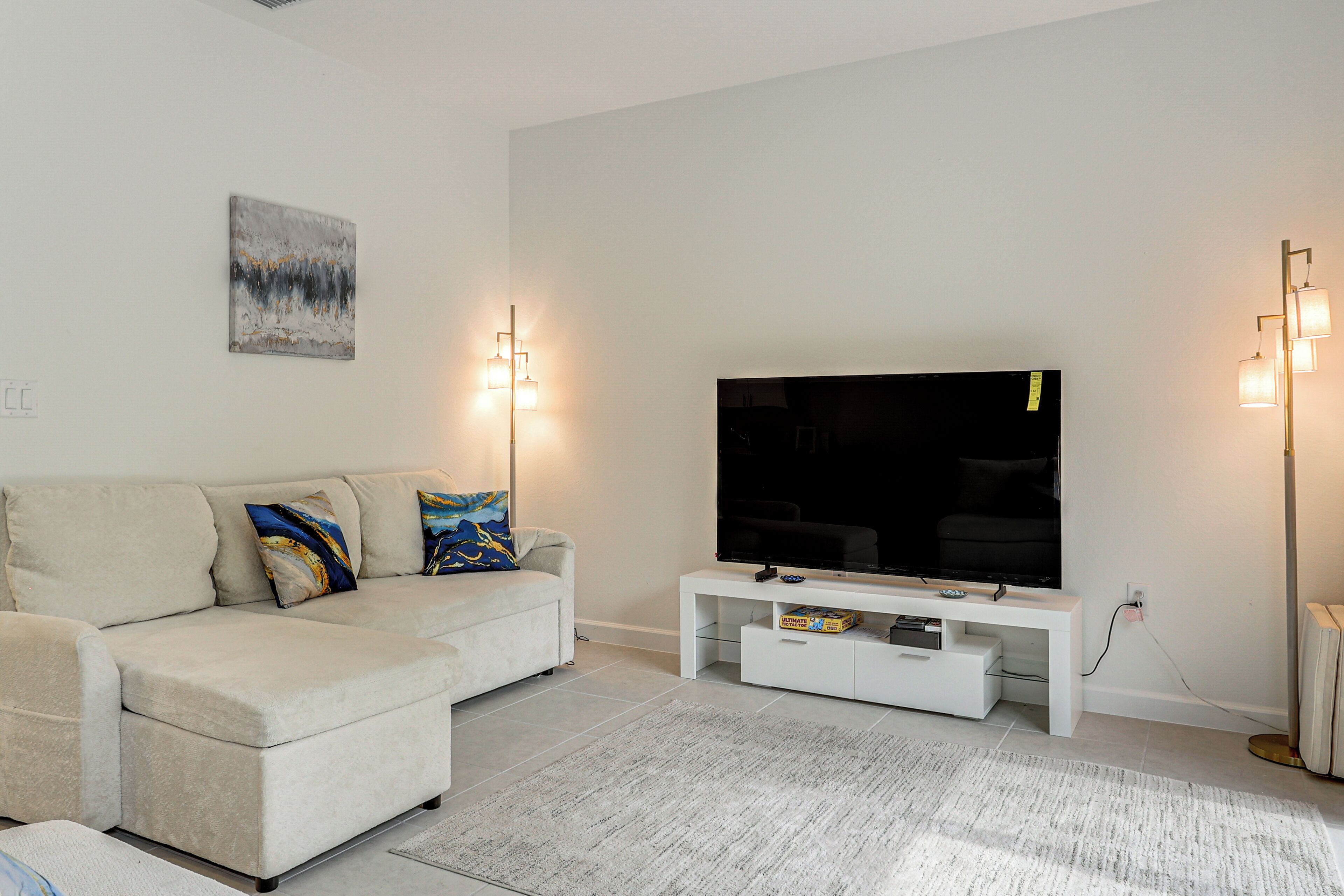 Una sala de estar moderna con un sofá, un televisor de pantalla plana y un mueble blanco para entretenimiento.