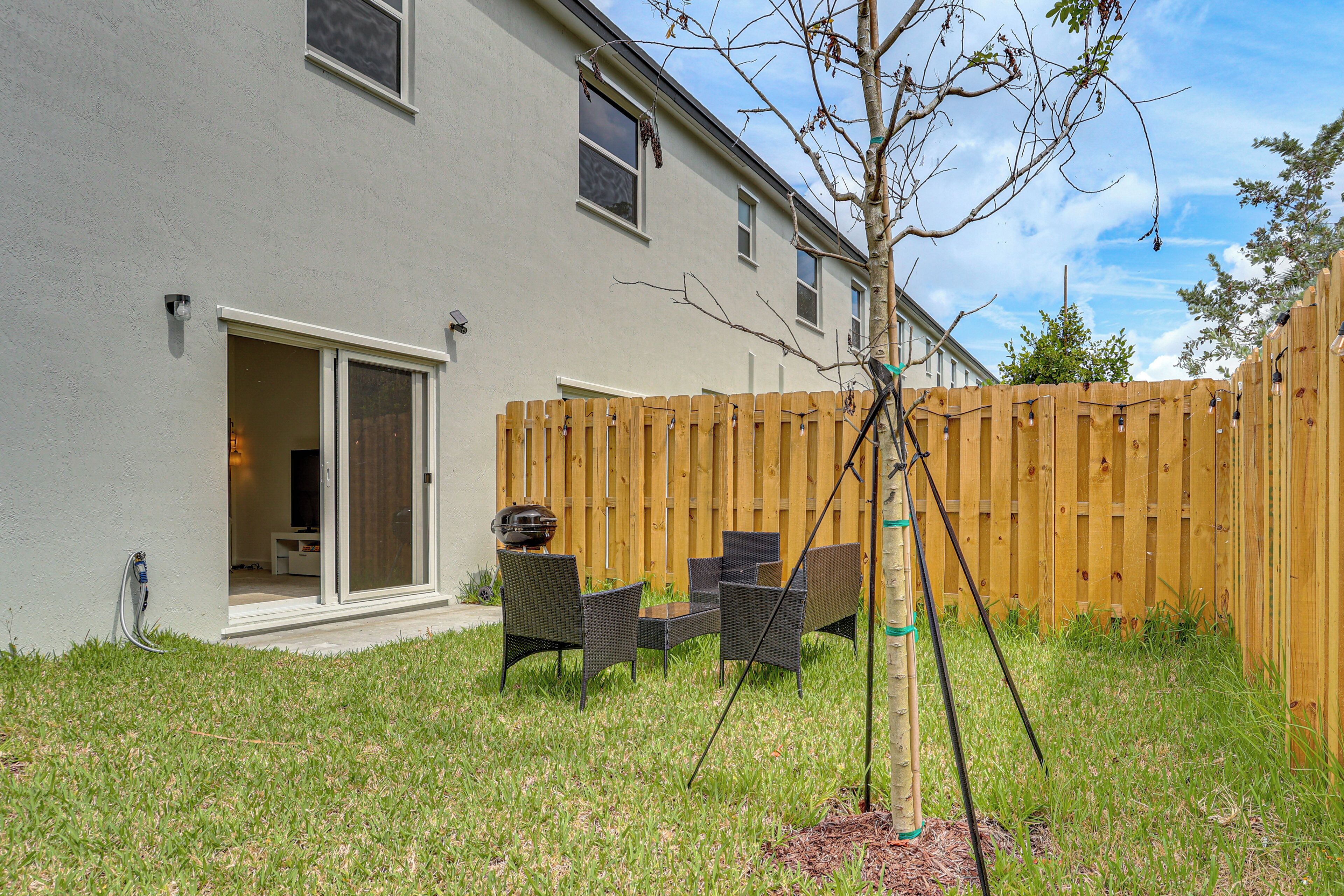A backyard with a patio, a wooden fence, and outdoor furniture.