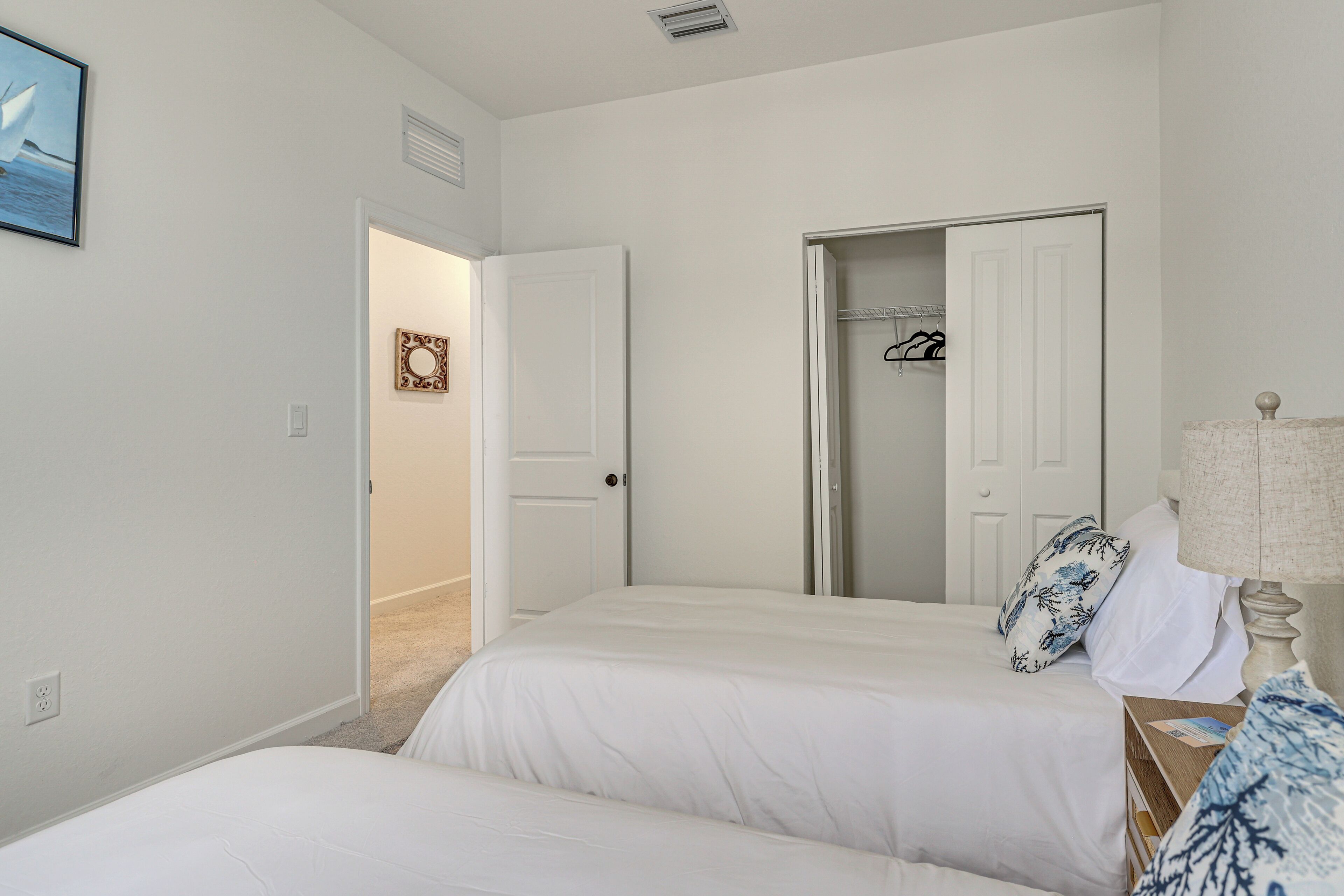A bedroom with two beds, a closet, and a door leading to another room.