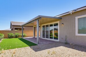 A modern house with a covered patio, a well-maintained lawn, and a gravel driveway.