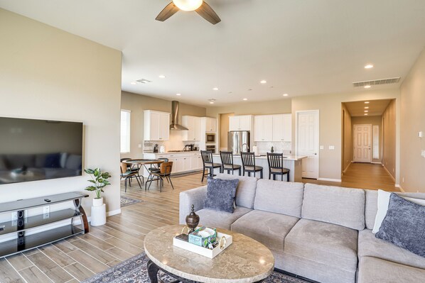A modern living room with a sofa, coffee table, TV, and dining area.