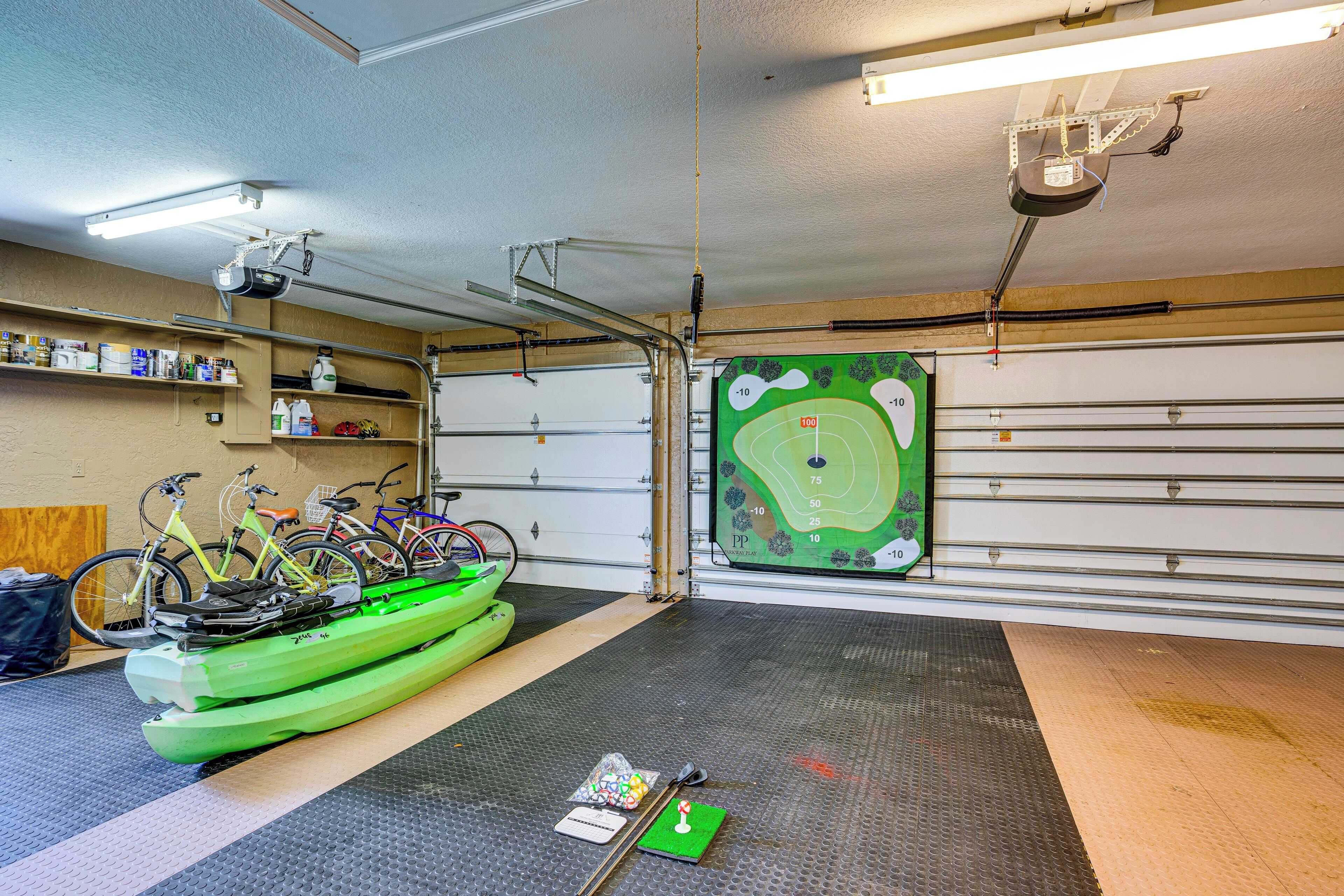 En garage med cykler, en grøn kajak og et kort over en golfbane på væggen.