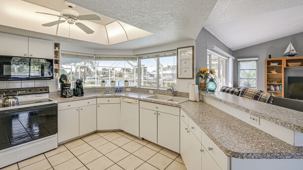 A kitchen with a built-in oven, a coffee maker, and a large window. - Walk to Port Charlotte Beach Park! Canal-front Gem (Port Charlotte)