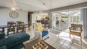 A spacious living area with a dining table, chairs, a sofa, a wicker chair, and a ceiling fan. - Walk to Port Charlotte Beach Park! Canal-front Gem (Port Charlotte)