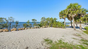 A beach with sand, palm trees, and a clear blue sky. - Walk to Port Charlotte Beach Park! Canal-front Gem (Port Charlotte)