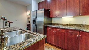Una cocina con encimeras de granito, electrodomésticos de acero inoxidable y armarios de madera.