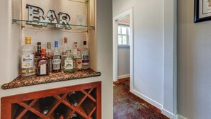 Una zona de bar con una estantería para vinos y diversas botellas de licores.