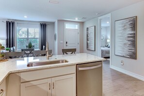 A modern kitchen with a built-in dishwasher, a dining area with a table and chairs, and a large window with curtains. - Work & Play! Home w/ Modern Comfort in Estero (Estero)