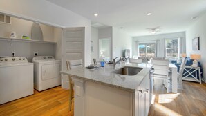 Una cocina moderna con electrodomésticos integrados, una isla central con un lavamanos y una zona de comedor con vistas.