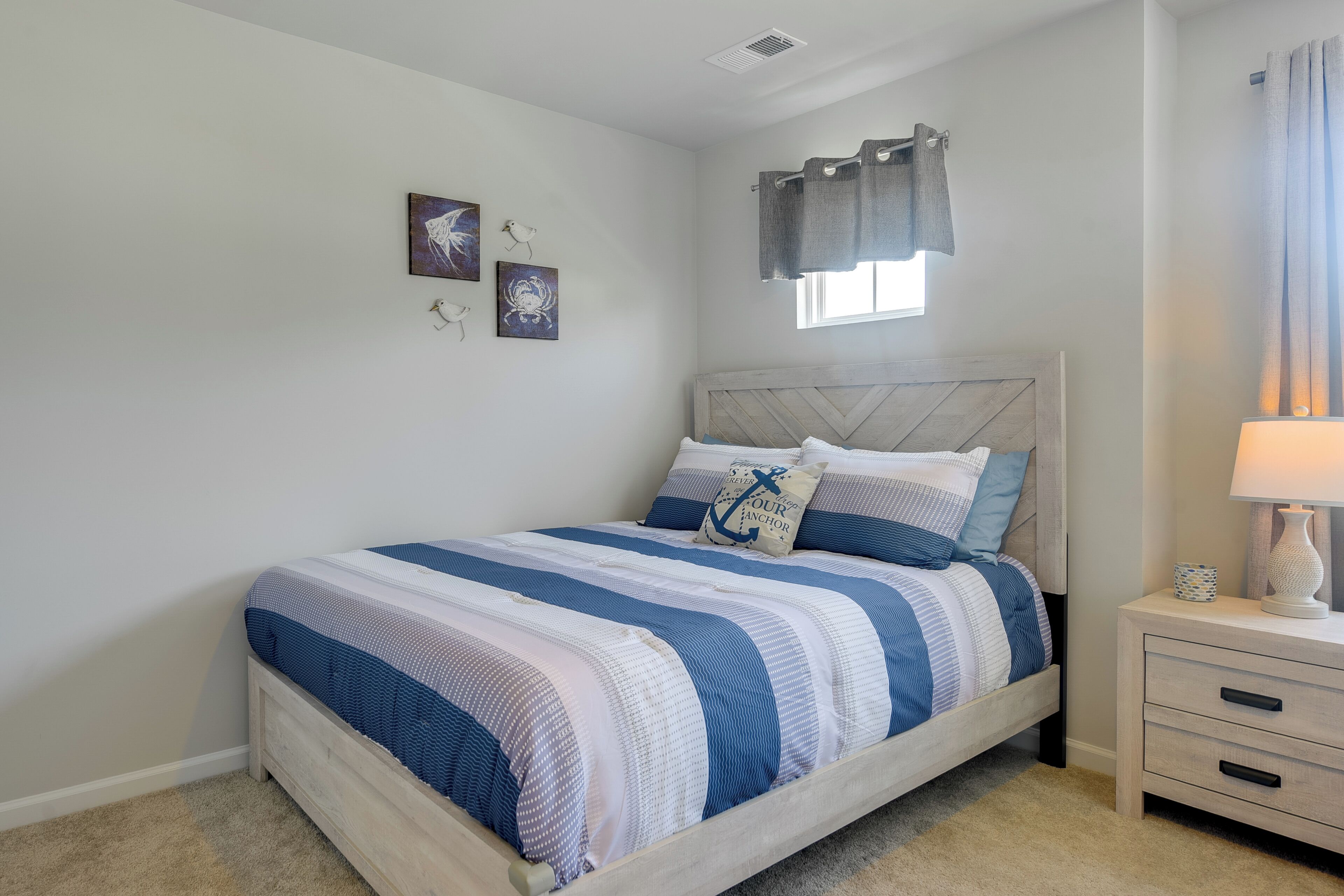 A bedroom with a bed, nightstand, and wall art.