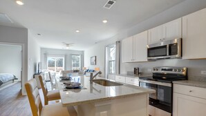 Una cocina moderna con armarios blancos, un microondas de acero inoxidable y una isla con asientos.